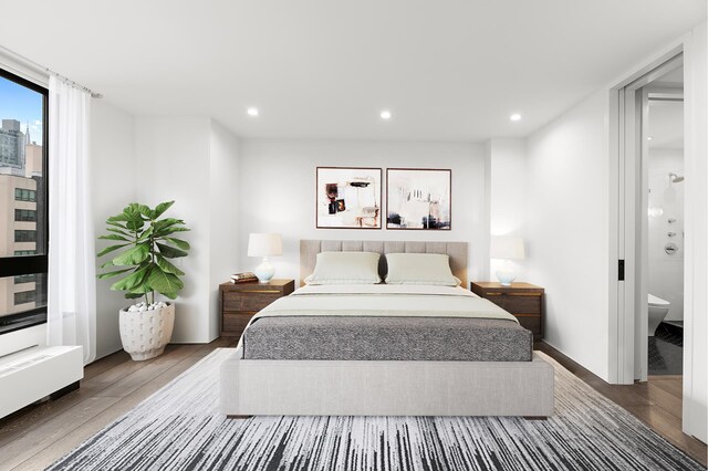 bedroom with ensuite bathroom and hardwood / wood-style floors