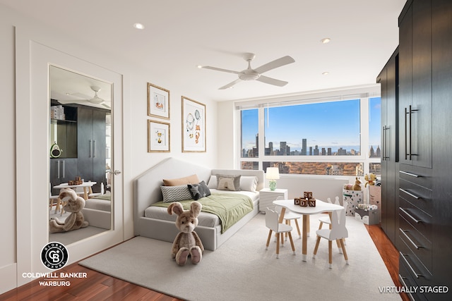 bedroom with floor to ceiling windows, a view of city, recessed lighting, and wood finished floors