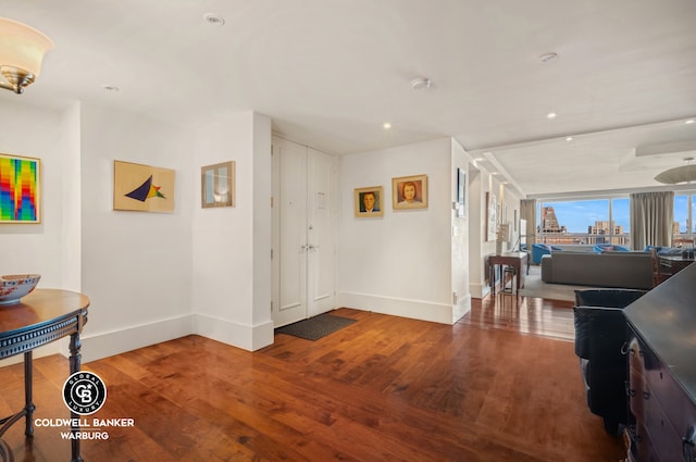 corridor with recessed lighting, baseboards, wood finished floors, and a view of city