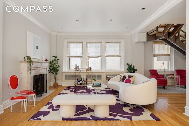 living room with ornamental molding, a high end fireplace, and light hardwood / wood-style floors