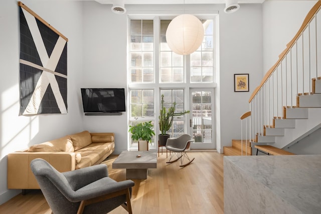 sitting room featuring stairway, a high ceiling, visible vents, and light wood-style floors