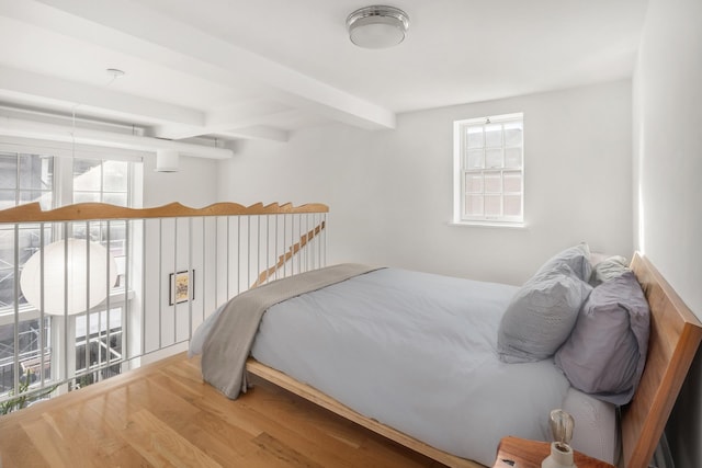 bedroom featuring wood finished floors and beam ceiling