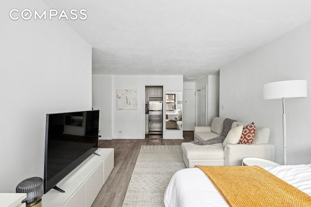 bedroom with wood finished floors and freestanding refrigerator