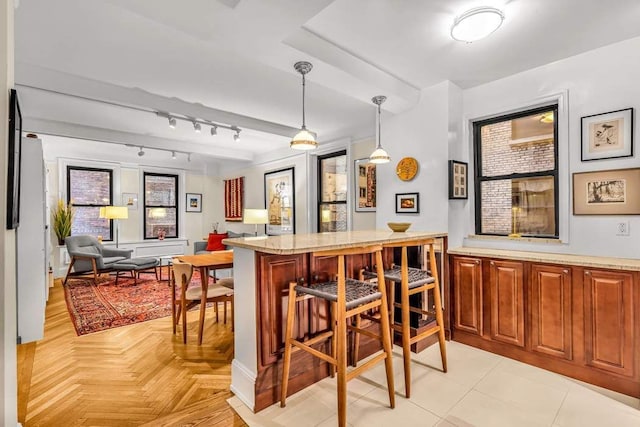 kitchen featuring rail lighting, a kitchen bar, kitchen peninsula, and hanging light fixtures