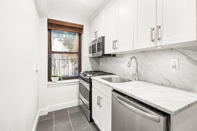 kitchen featuring white cabinets, light stone counters, appliances with stainless steel finishes, and sink