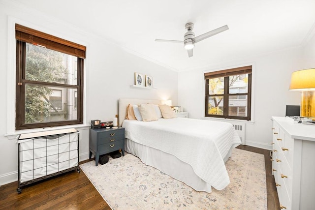 bedroom featuring radiator heating unit, multiple windows, dark hardwood / wood-style floors, and ceiling fan