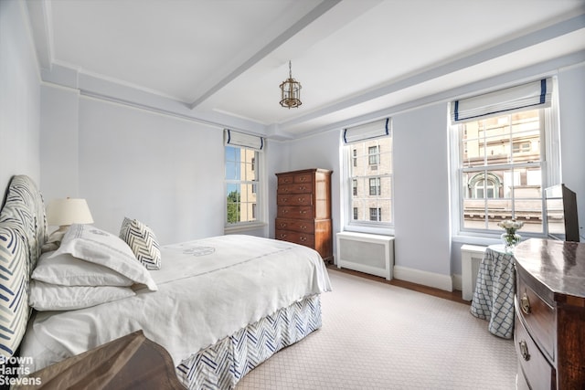 bedroom featuring multiple windows, light colored carpet, radiator, and beam ceiling