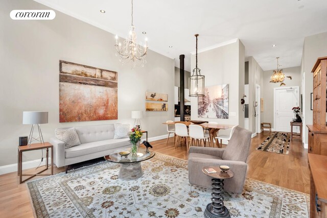 living room featuring an inviting chandelier, crown molding, and light hardwood / wood-style flooring