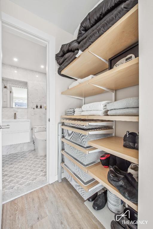 walk in closet with light hardwood / wood-style flooring