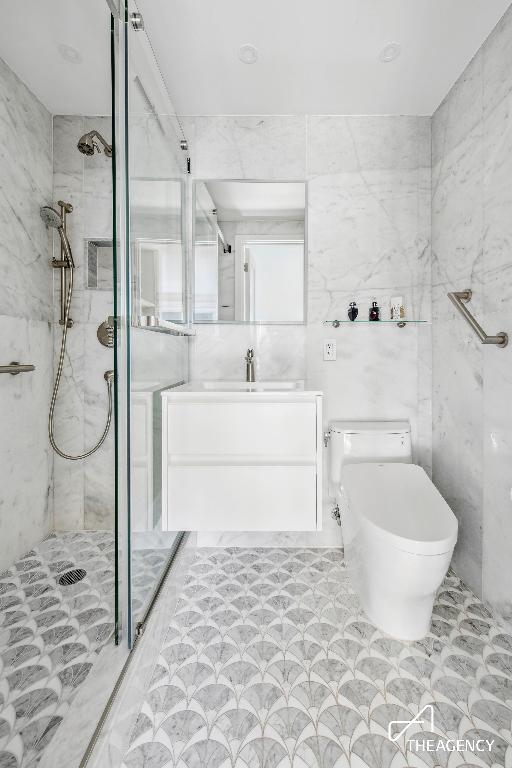 bathroom with a tile shower, toilet, and vanity