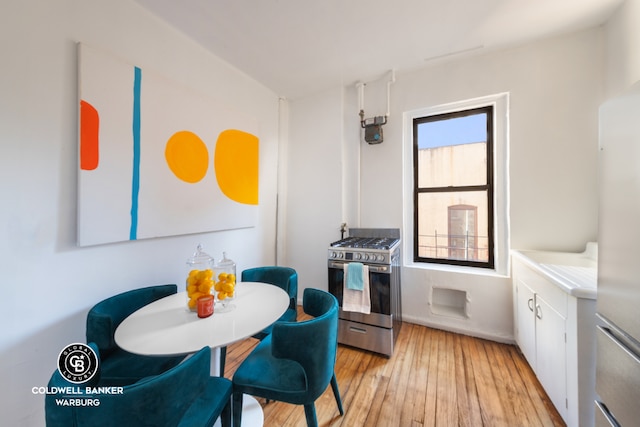 kitchen featuring white cabinets, light hardwood / wood-style floors, stainless steel range with gas stovetop, and a healthy amount of sunlight