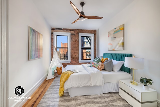 bedroom featuring brick wall, ceiling fan, and light hardwood / wood-style flooring