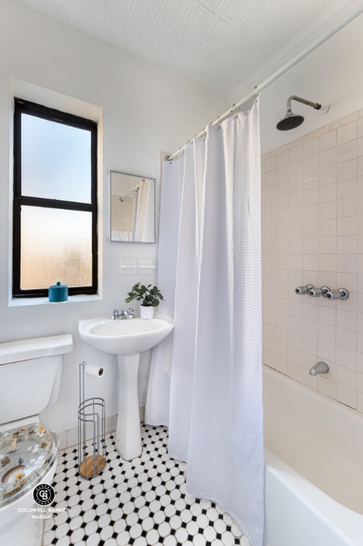 full bathroom with shower / tub combo with curtain, tile patterned floors, toilet, and sink