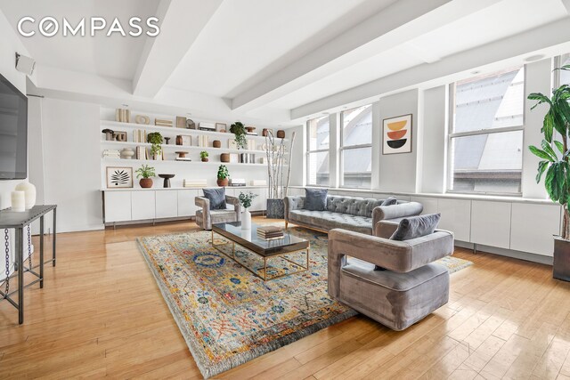 living room featuring beamed ceiling and light hardwood / wood-style floors