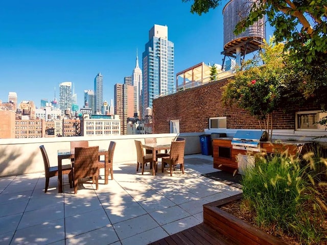 view of patio featuring a view of city, exterior kitchen, outdoor dining space, and a grill