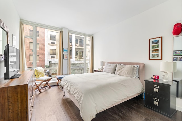 bedroom featuring access to exterior, expansive windows, and dark wood finished floors