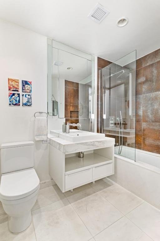 full bathroom with enclosed tub / shower combo, vanity, tile patterned floors, and toilet