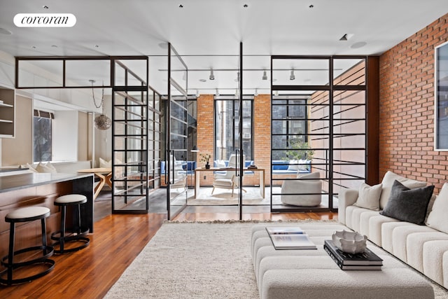 living room featuring expansive windows, wood-type flooring, and brick wall