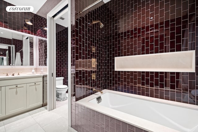 full bathroom with toilet, vanity, tile walls, tile patterned floors, and tiled shower / bath combo