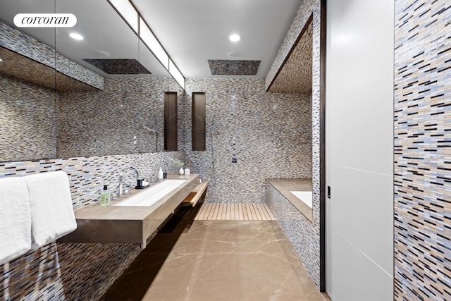 bathroom featuring a shower, sink, and tile walls