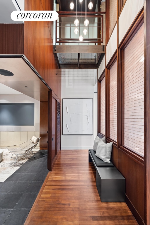 hall with a towering ceiling, an inviting chandelier, and dark hardwood / wood-style flooring