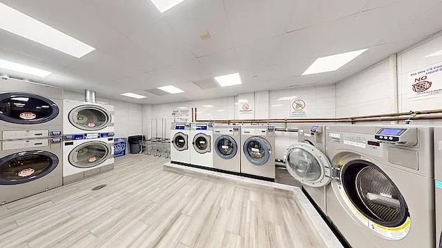 laundry area featuring stacked washer / dryer, independent washer and dryer, and light hardwood / wood-style floors