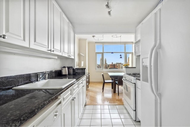 kitchen featuring sink, white cabinets, dark stone counters, light tile patterned floors, and white appliances