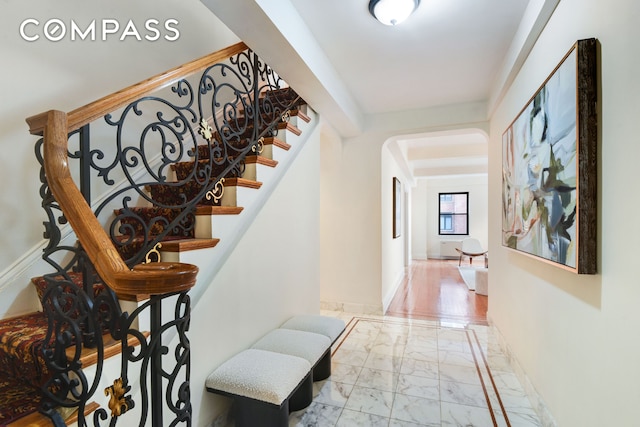 stairs featuring arched walkways, marble finish floor, and baseboards