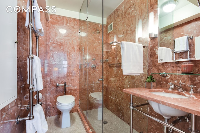 full bathroom featuring toilet, a sink, visible vents, tile walls, and tiled shower