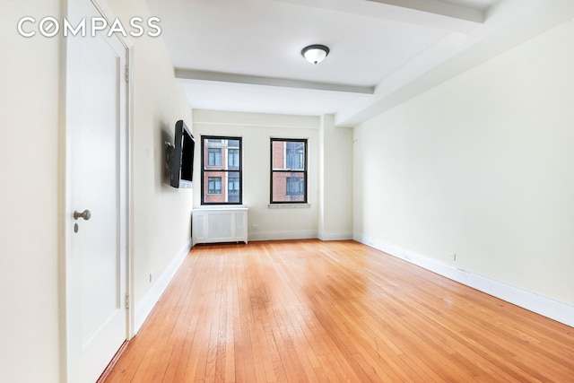 unfurnished room featuring light wood-type flooring, beam ceiling, baseboards, and radiator heating unit