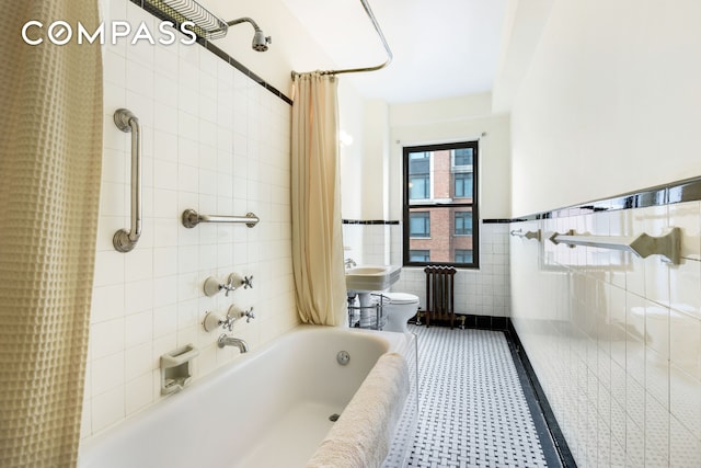 bathroom with a wainscoted wall, toilet, shower / bath combo with shower curtain, and tile walls