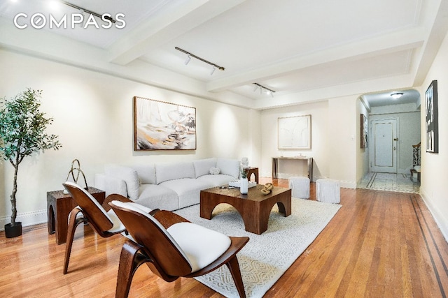 living room featuring beamed ceiling, track lighting, and light hardwood / wood-style floors