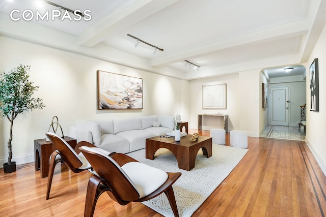 living area with light wood-style flooring, track lighting, baseboards, and beamed ceiling