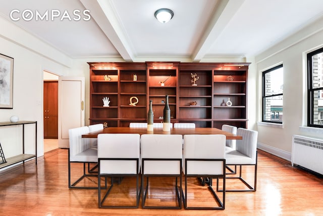 dining space featuring crown molding, light wood-style flooring, radiator heating unit, beamed ceiling, and baseboards