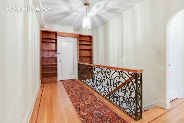 hallway featuring wood-type flooring, arched walkways, and baseboards