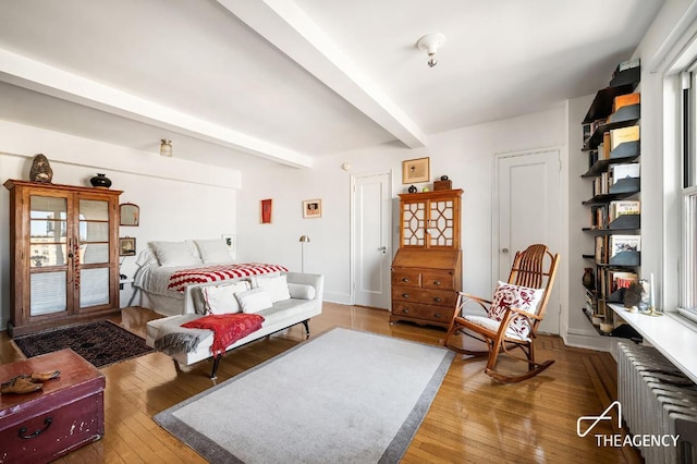 bedroom featuring radiator, hardwood / wood-style flooring, and beamed ceiling