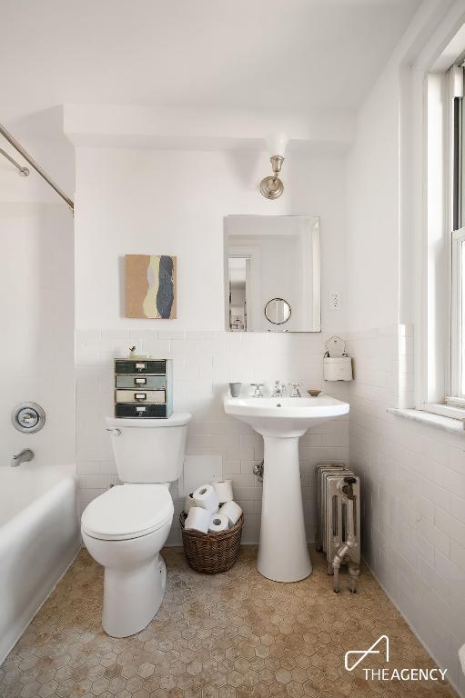 bathroom with radiator heating unit, toilet, and  shower combination