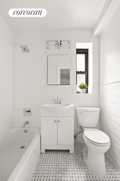 full bathroom with toilet, tile walls, tiled shower / bath, and vanity