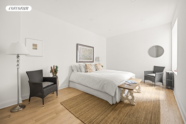 bedroom featuring light wood finished floors, radiator, and baseboards