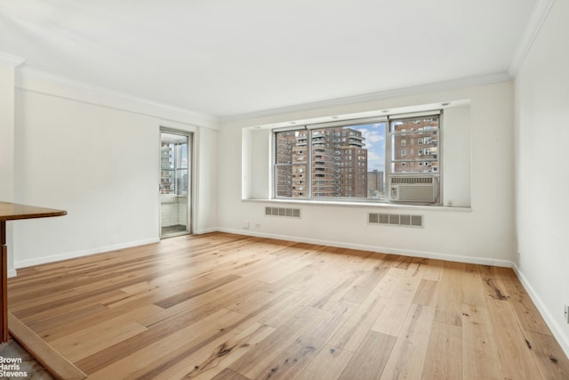 spare room with crown molding, baseboards, and wood finished floors