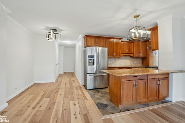 kitchen with stainless steel fridge with ice dispenser, ornamental molding, decorative backsplash, brown cabinets, and light wood finished floors