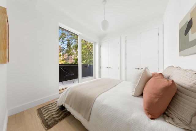 bedroom with access to exterior, wood finished floors, and baseboards