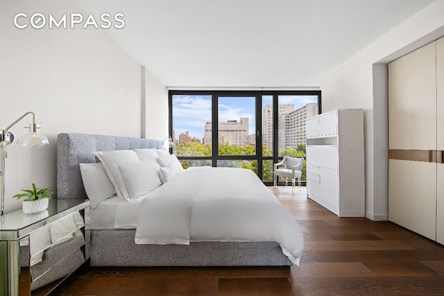 bedroom with dark hardwood / wood-style floors and a wall of windows