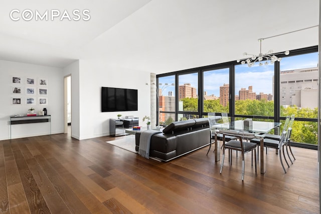 living room featuring a wealth of natural light, a notable chandelier, floor to ceiling windows, and wood finished floors