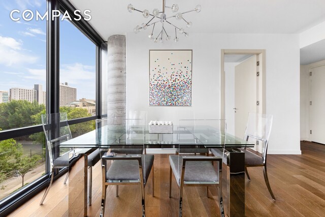 dining space featuring baseboards, a chandelier, floor to ceiling windows, wood finished floors, and a view of city