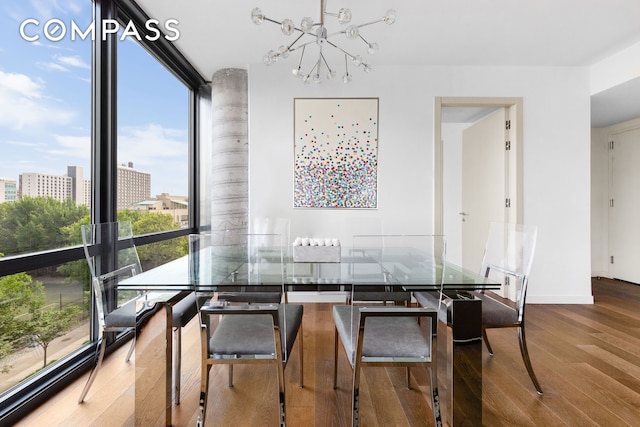 dining space with baseboards, a city view, expansive windows, an inviting chandelier, and wood finished floors