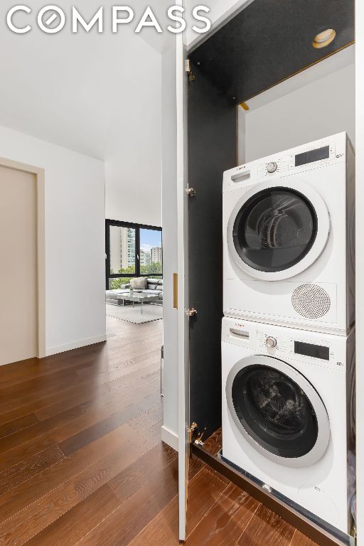 laundry room featuring dark hardwood / wood-style floors and stacked washing maching and dryer