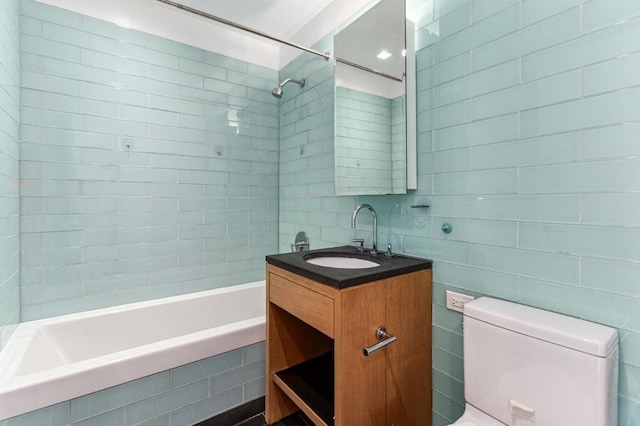 full bathroom with vanity, toilet, tiled shower / bath combo, and tile walls