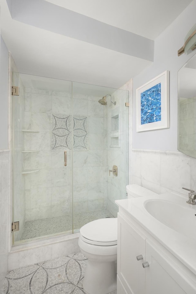 bathroom with a stall shower, tile walls, toilet, and vanity