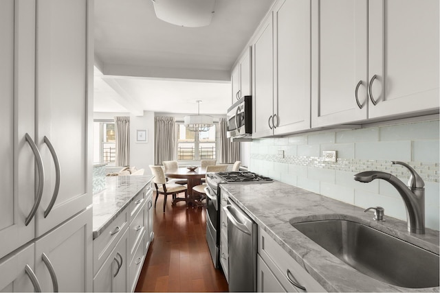 kitchen with light stone countertops, white cabinetry, appliances with stainless steel finishes, and a sink